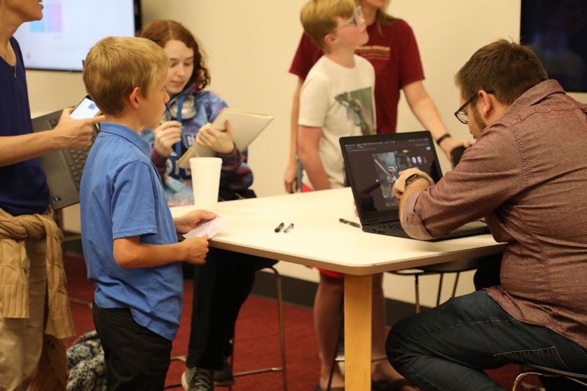 Derek Kooi showing AI tools to a group of children